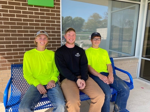 President Jeffrey Bemis, Secretary Garrett Nesheim, and Vice President Izak Gruber sitting on a bench. 