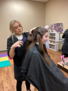 Cosmetology Student Abby Denhartigh cutting a girl's hair.