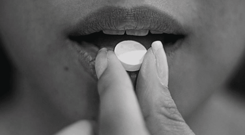 Person swallowing a pill.