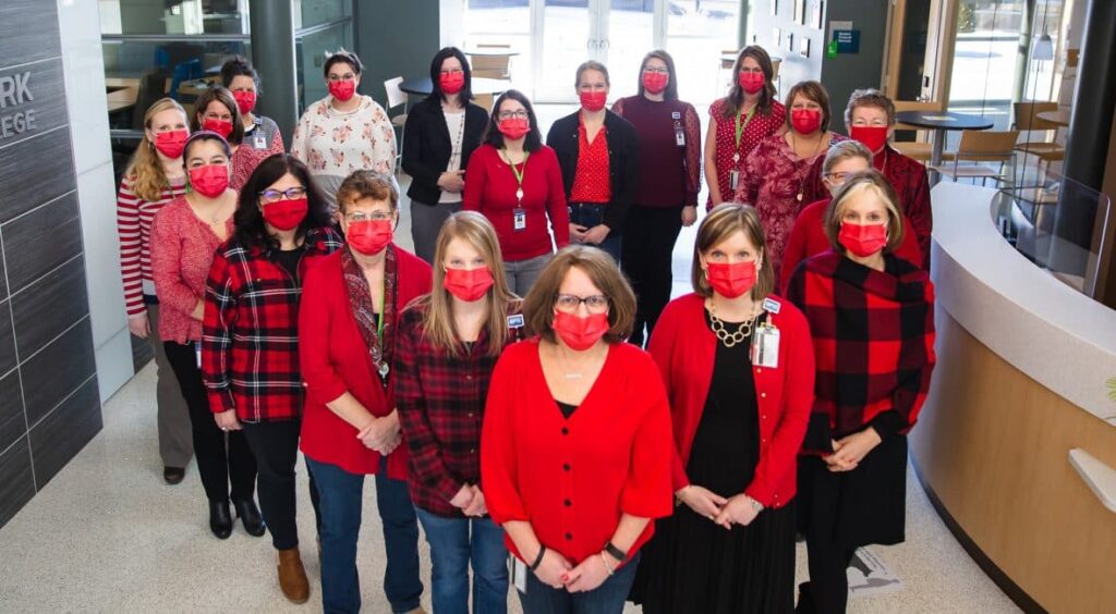 21 Moraine Park employees all dressed in red standing in the shape of a heart.