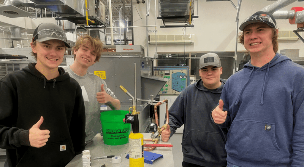 Four students in lab with their thumbs up