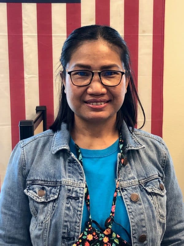 Student Suchanat Buckman standing in front of U.S. flag.