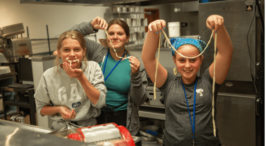 Three students cooking in the kitchen with Moraine Park Culinary Arts instructor.