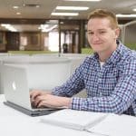 Male business student using laptop.