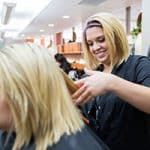 female cosmetology student curling a client's hair