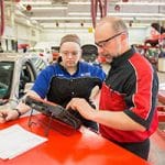 Happy Moraine Park students fixing a red car.