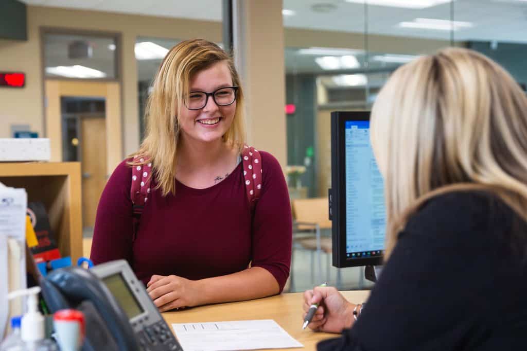 Student talking to advisor at a desk.