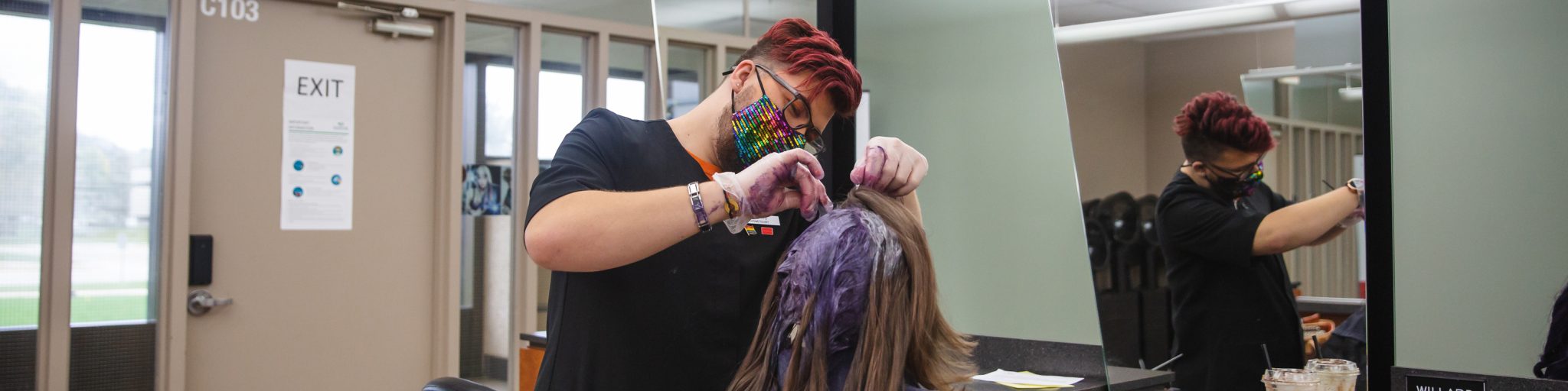 cosmetology student wearing a mask and doing hair on a client
