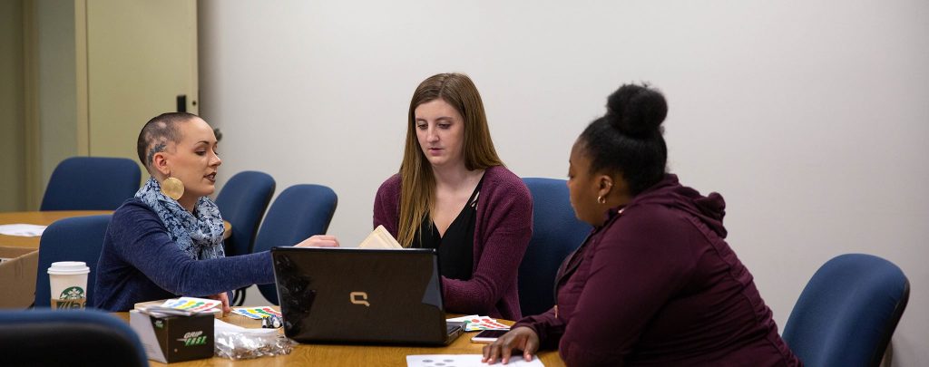 three female students working on laptop