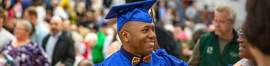 male student graduating from college wearing cap and gown