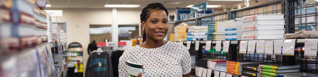 female student buying textbooks in bookstore