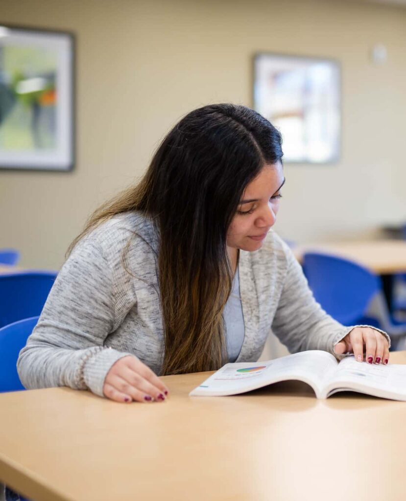 One students sitting at the table and studying a book.