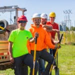 Four cheerful Gas Utility Construction and Service students with shovels standing outside in the sun.