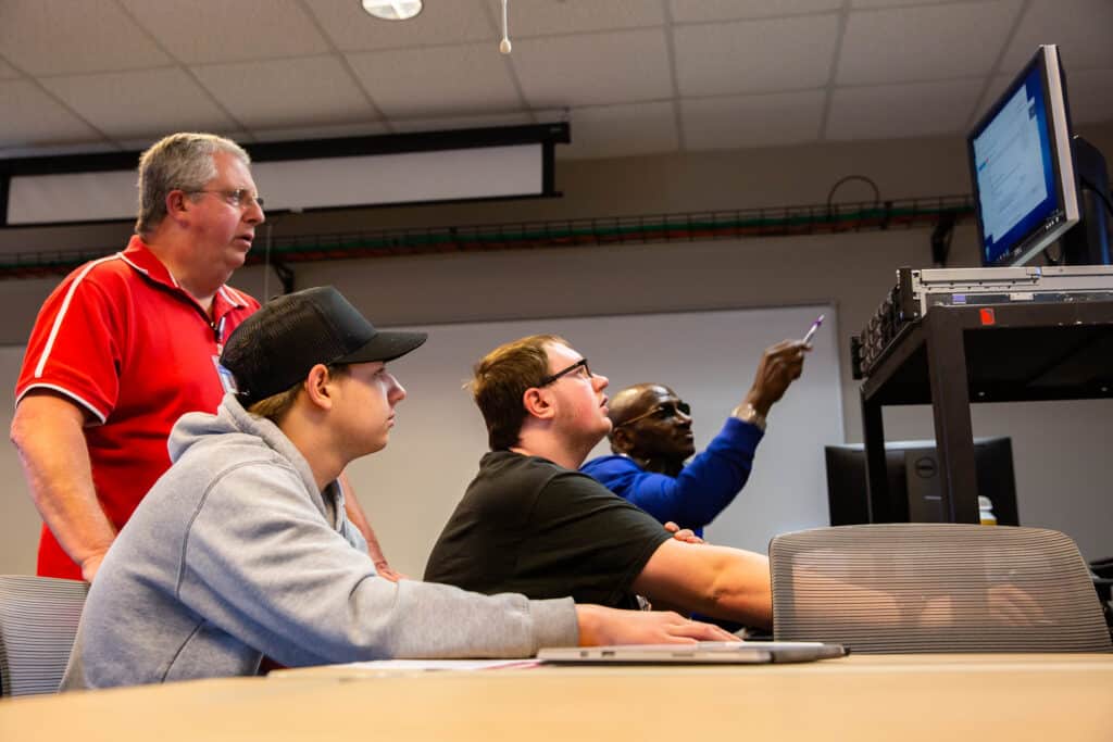 Three students and one teacher solving a problem on a desktop screen.