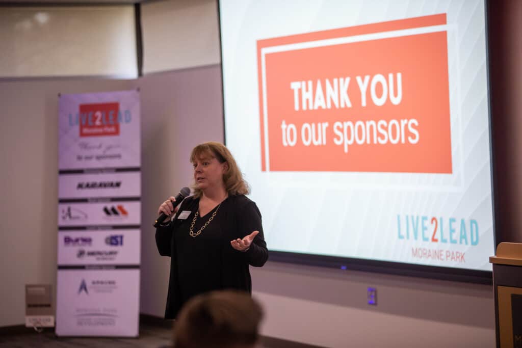 Presenter speaking on the front podium at a conference.