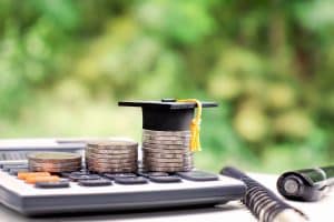 money and small graduation cap on a calculator