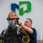 An instructor helping a fire figher secure their helmet.