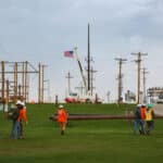 EPD students approaching the training field with electrical masts. A USA flag is showing at a mast in the background.