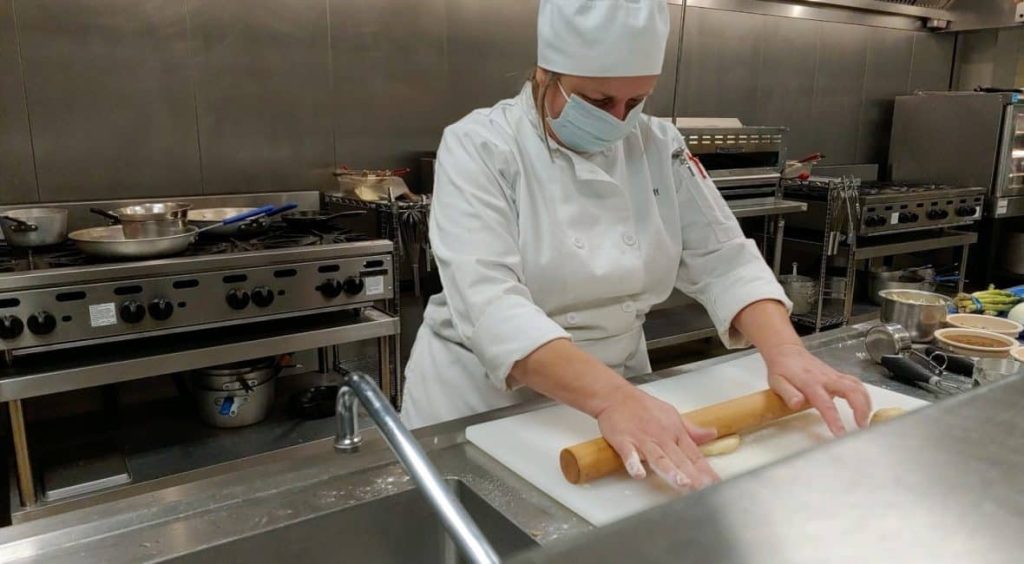 Moraine Park Culinary Arts students in the kitchen rolling dough.