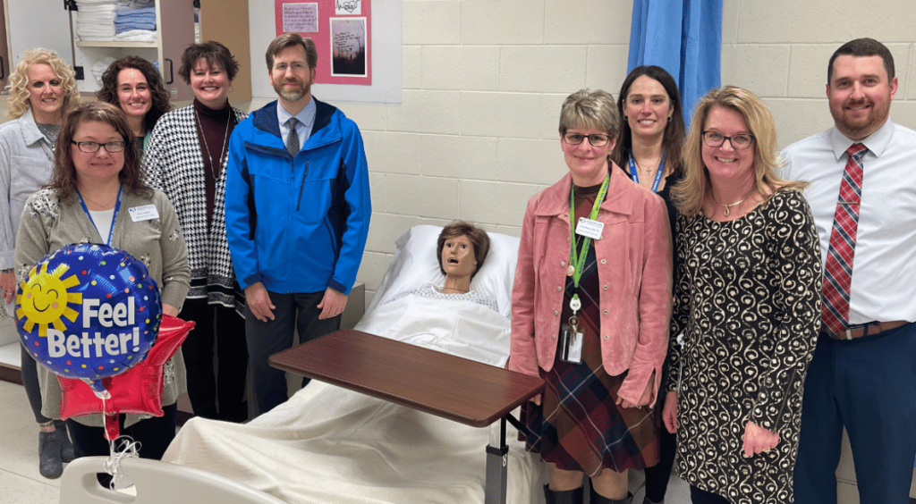 Community Members standing next to a dummy in a hospital bed