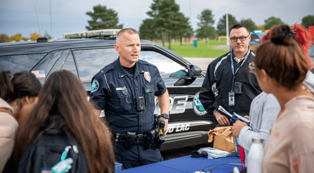 Two policemen talking to high school students.