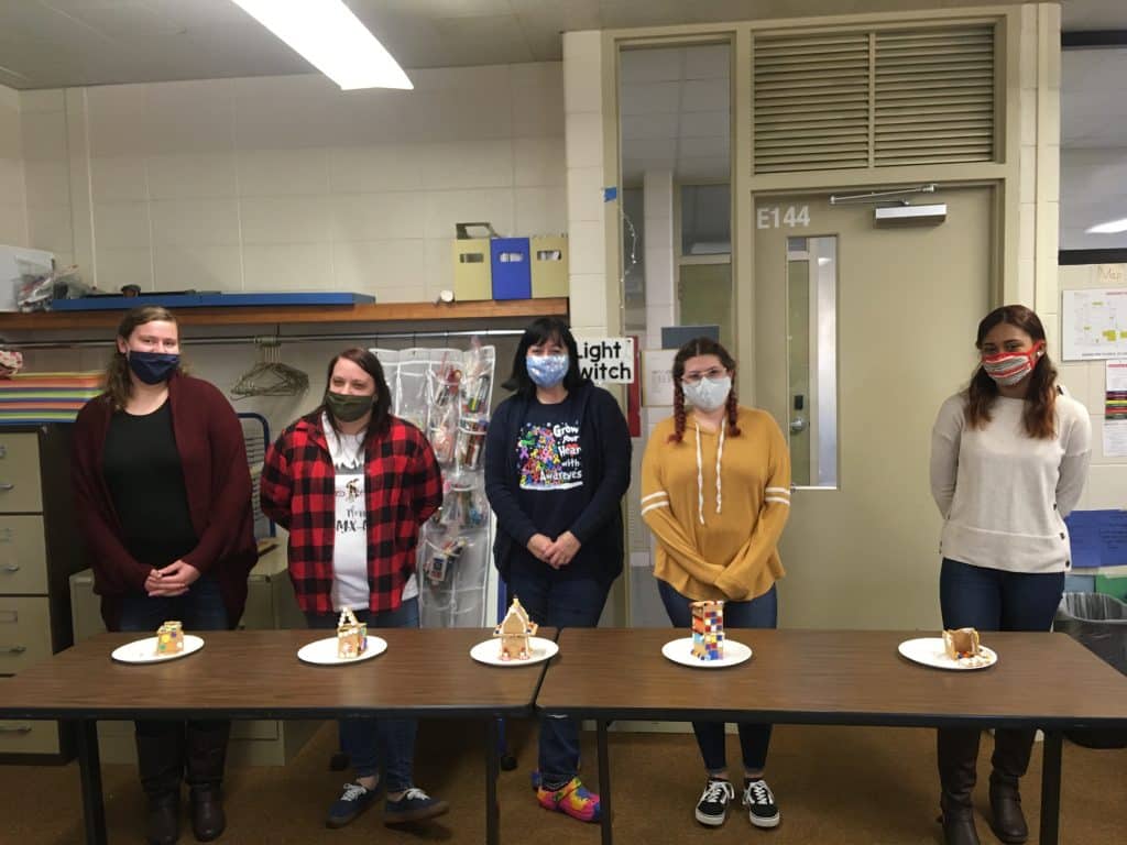 Early Childhood Education students standing in front of a table with cake on it.