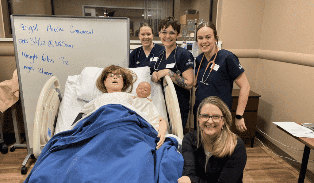 Nursing students in the simulation center smiling at camera