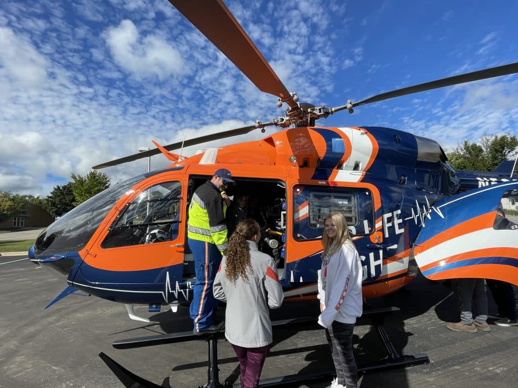West Bend High School Emergency Medical Technician (EMT) class members standing in front of helicopter. 