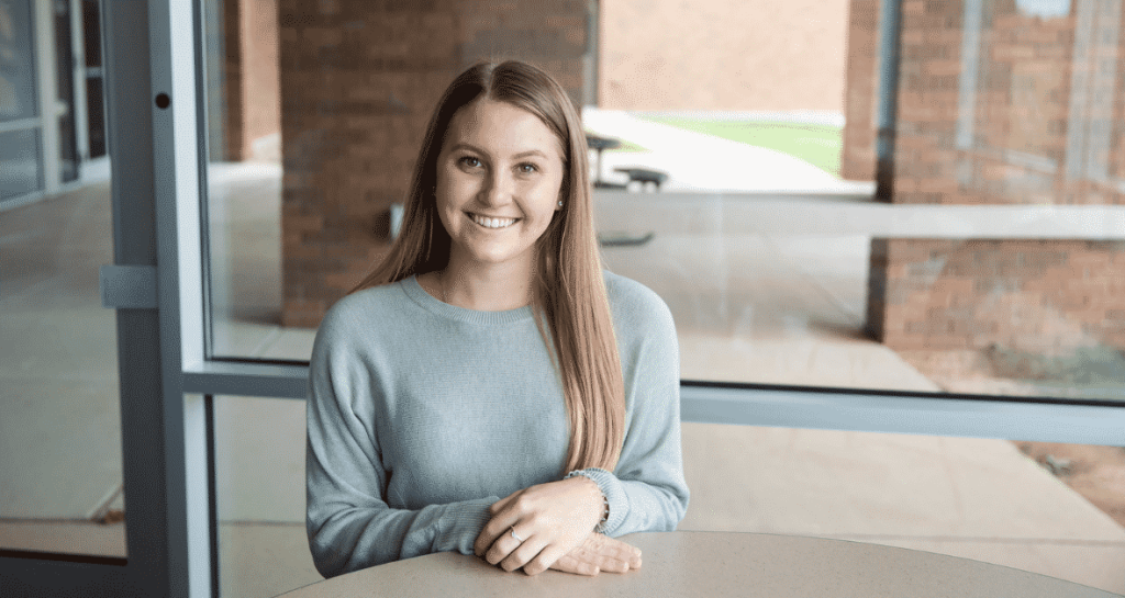 Moraine Park Technical College student Jordyn Schmitt sitting at desk smiling into the camera.