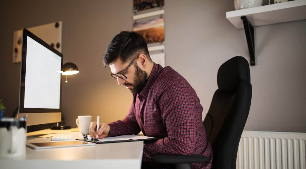 Young man sitting in front of his computer working from home.