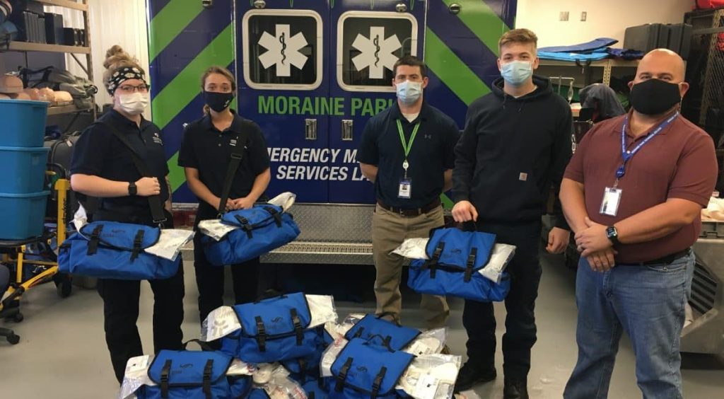 Four Moraine Park EMT students in full gear standing in front of an EMT vehicle.