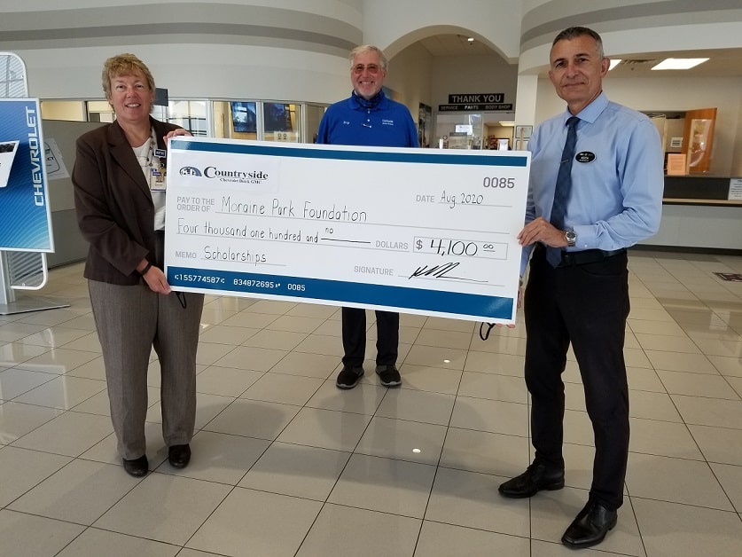 Moraine Park President Bonnie Baerwald and two representatives from Countryside auto Group holding a gigantic check.