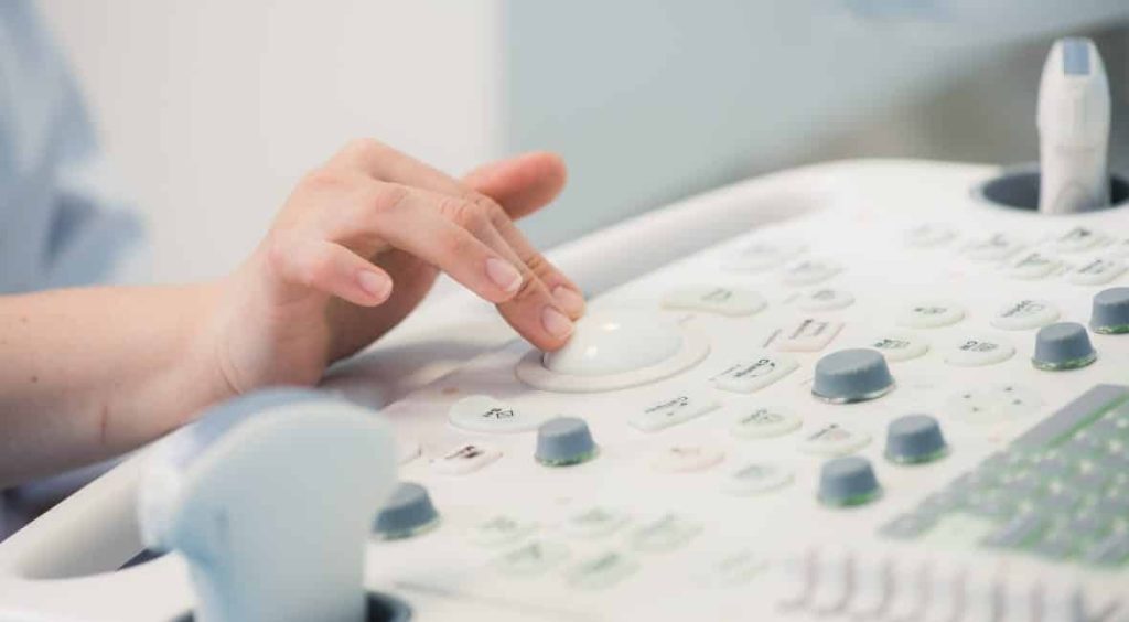 Sonographer operating a sonography machine.