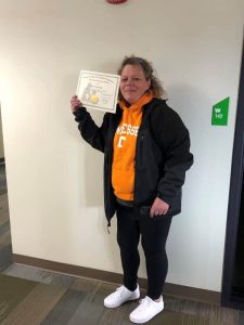 Student Justine proudly holding up her certificate for the camera.