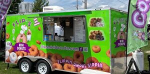 Flips Mini Donuts Food Truck. It's green with images of different kinds of doughnuts on it. 