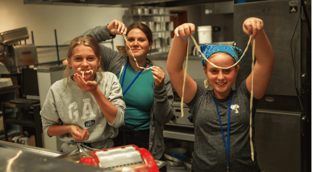 Three students cooking in the kitchen with Moraine Park Culinary Arts instructor.
