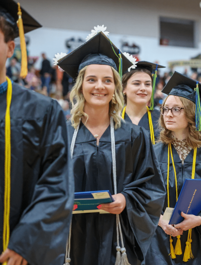 Morgan Schueler standing next to other graduates in commencement gowns.