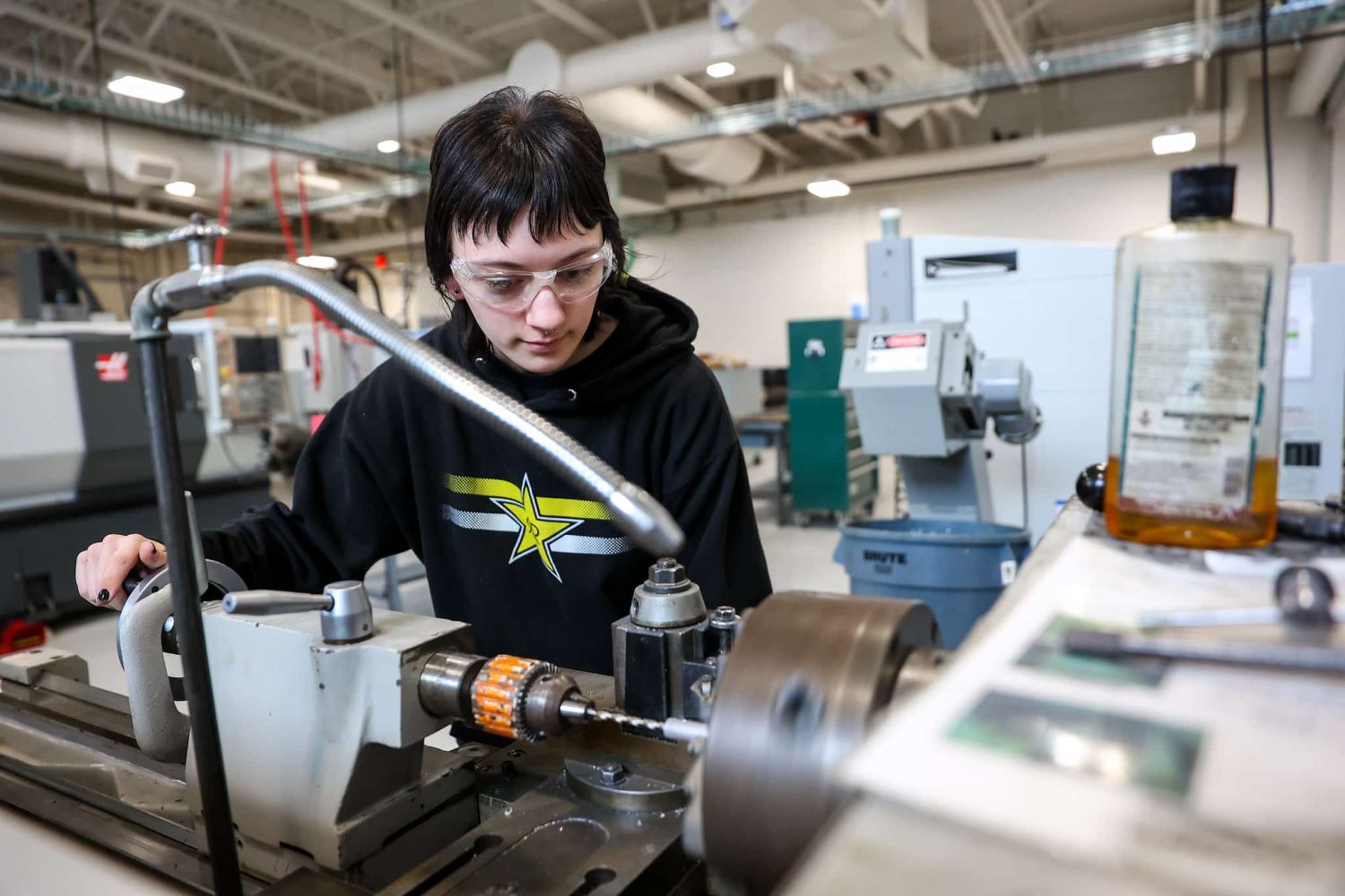 Taryn Reese operating a CNC machine wearing goggles.