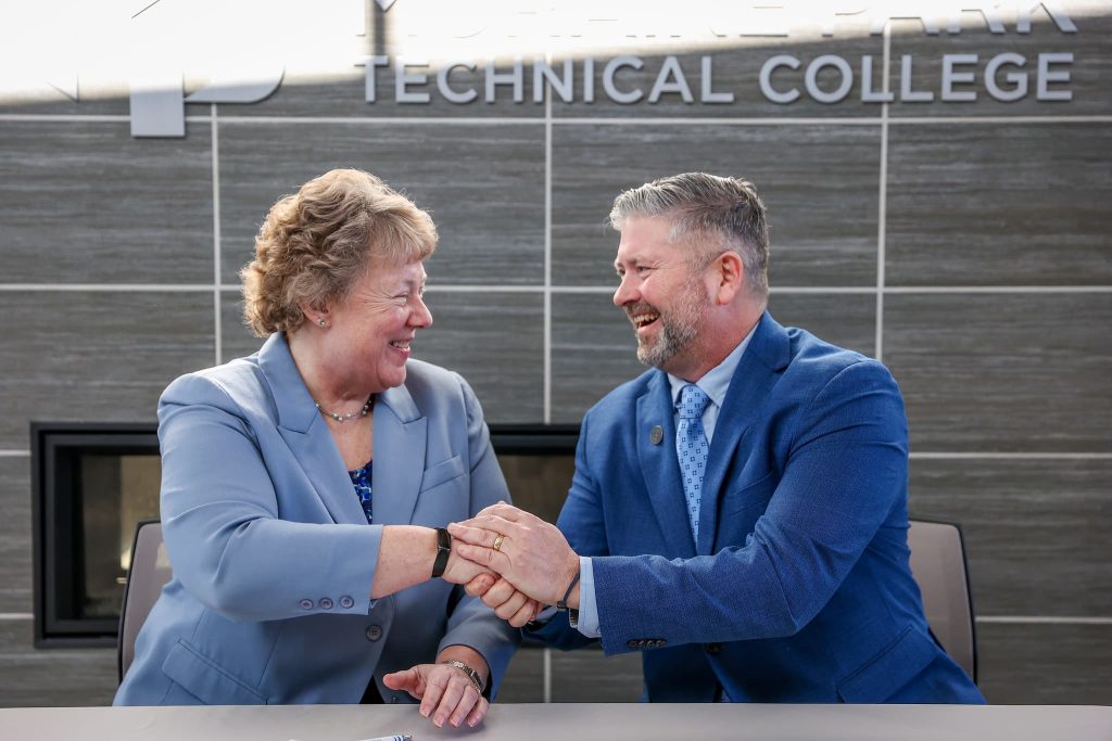 Bonnie Baerwald and Aaron Sadoff shaking hands at the transfer agreement signing.