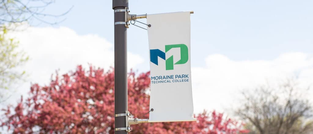 Moraine Park Technical College flag with logo outside on a light-pole