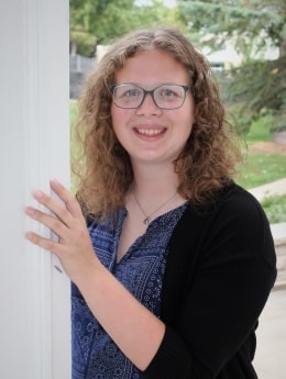 Moraine Park student Miya Gruner standing in front of trees and happily smiling into the camera.