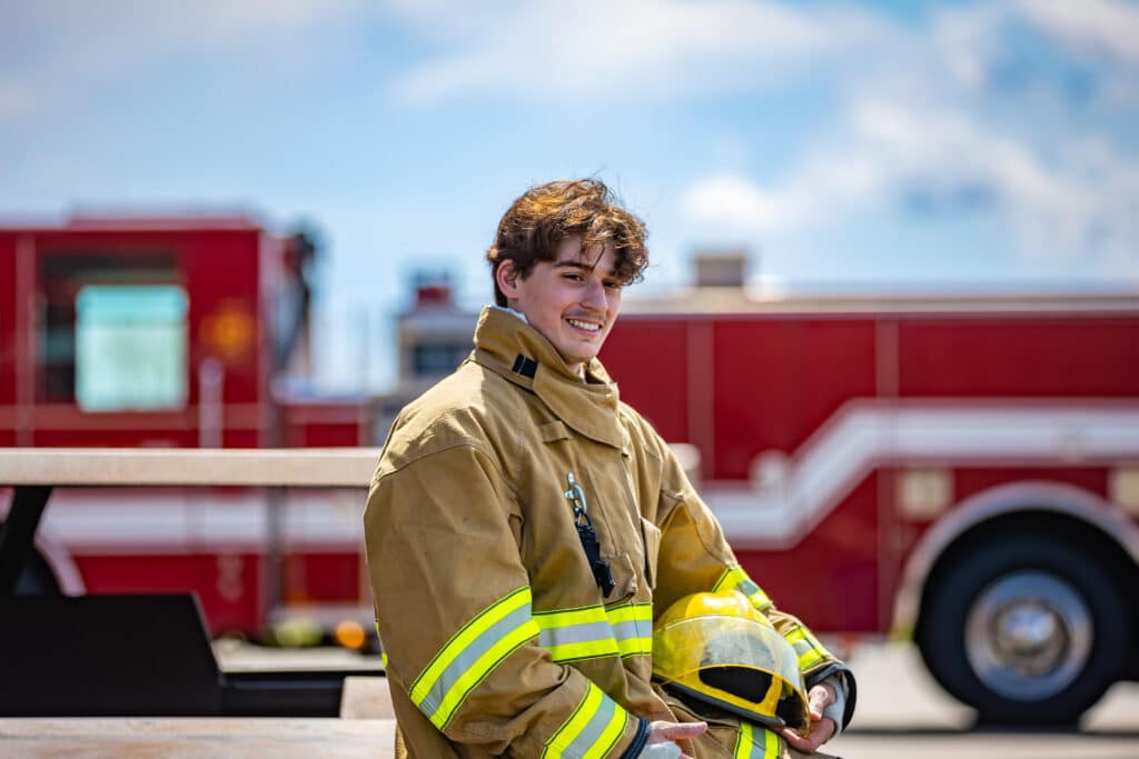 Moraine Park Fire Protection Technician student in full gear standing in front of a fire truck.