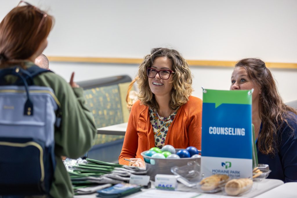 Two Moraine Park counselors talking to a student at a table with counseling flyers.
