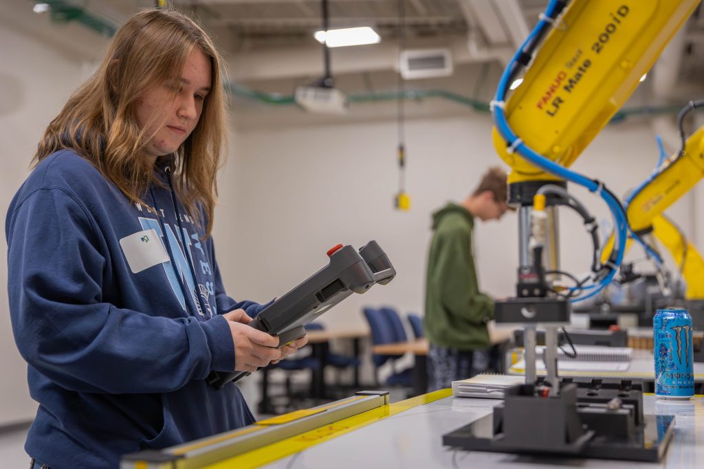 High school student controlling a mechanical arm with a joystick during Moraine Park's career experiences event.