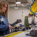 High school student controlling a mechanical arm with a joystick during Moraine Park's career experiences event.