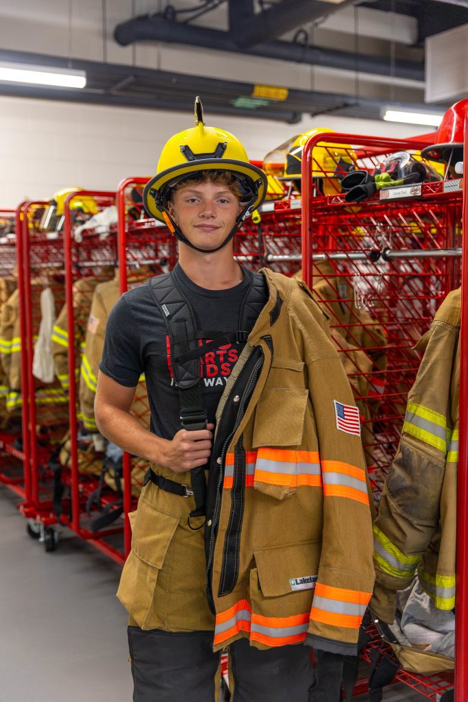 High School student wearing firefighter uniform during a career experience event at Moraine Park.