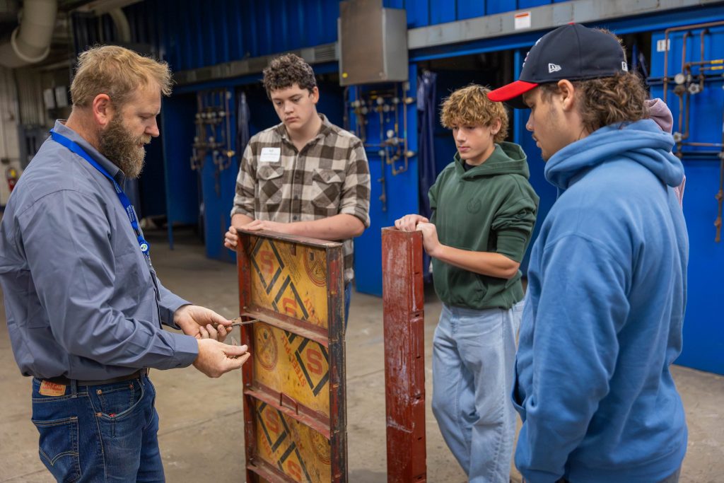High school students learning about handling materials for manufacturing tasks.