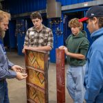 High school students learning about handling materials for manufacturing tasks.