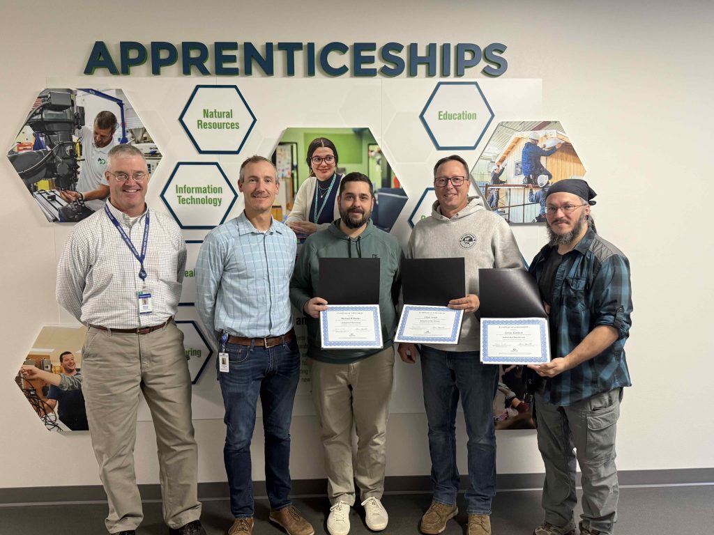 Moraine Park industrial electrician apprentice completers smiling in a line with their instructors