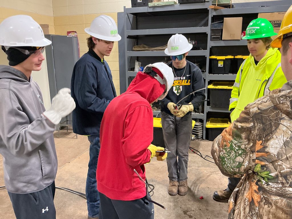 High school students wearing hard hats doing an exercise with wires to learn more about Moraine Park's Electricity program.
